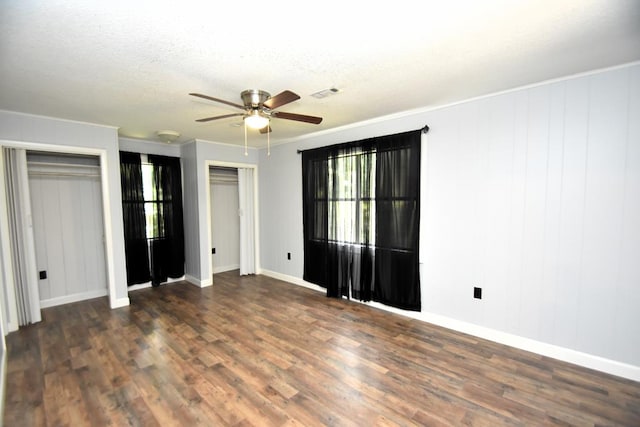 145 Deerpath St, Ozark, AL 36360 - unfurnished bedroom featuring multiple windows, dark wood-style flooring, two closets, baseboards, and a textured ceiling