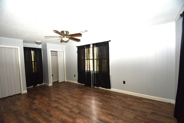 unfurnished bedroom with dark wood-type flooring, multiple closets, visible vents, and baseboards