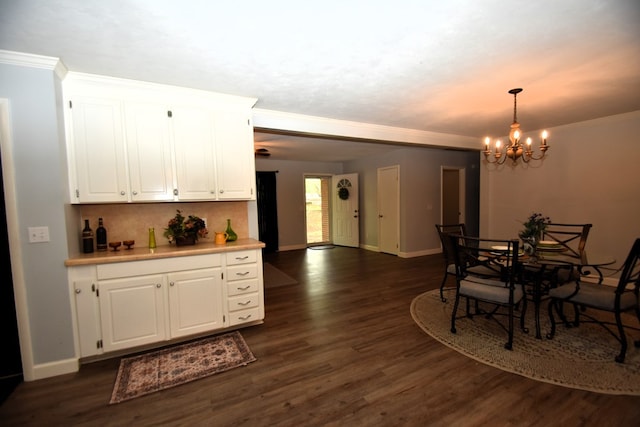 kitchen with an inviting chandelier, white cabinets, crown molding, and dark wood finished floors