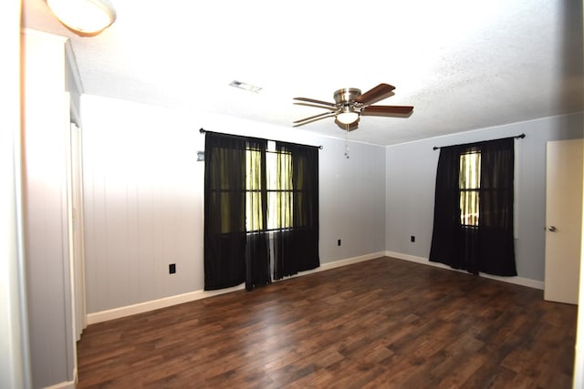 empty room with dark wood-style flooring, visible vents, baseboards, and ceiling fan