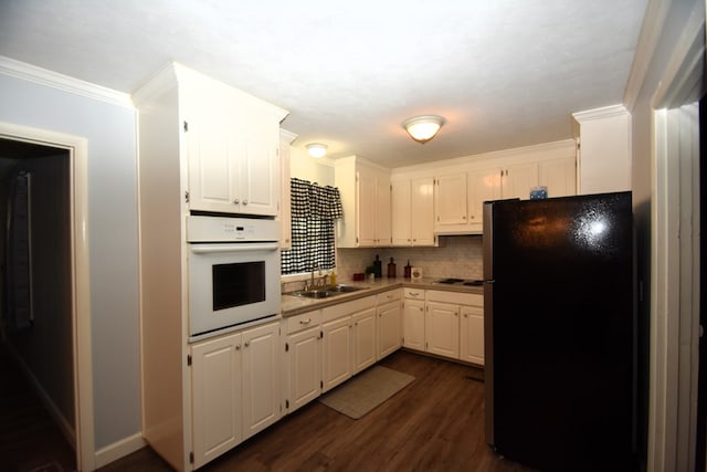 kitchen featuring white cabinetry, oven, electric stovetop, a sink, and freestanding refrigerator