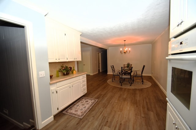 kitchen featuring light countertops, oven, a chandelier, white cabinets, and wood finished floors