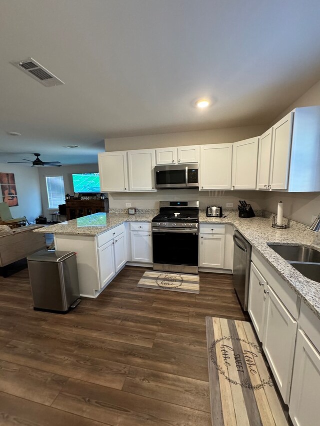 kitchen with ceiling fan, white cabinets, light stone countertops, and dark wood-type flooring