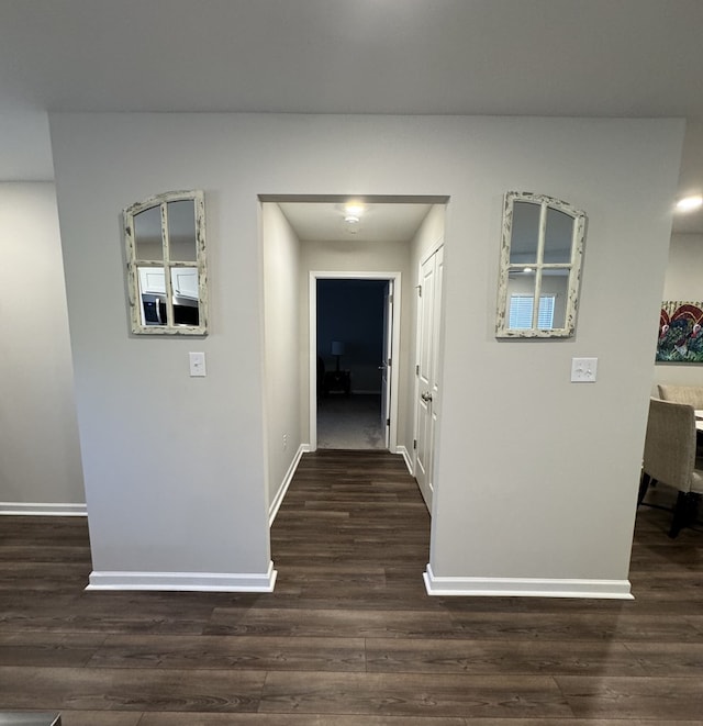 corridor featuring baseboards and dark wood-style floors