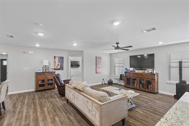 living area with dark wood finished floors, baseboards, and a ceiling fan