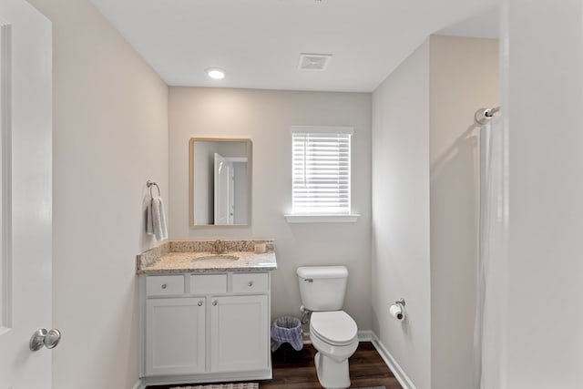 bathroom featuring vanity, wood finished floors, baseboards, visible vents, and toilet
