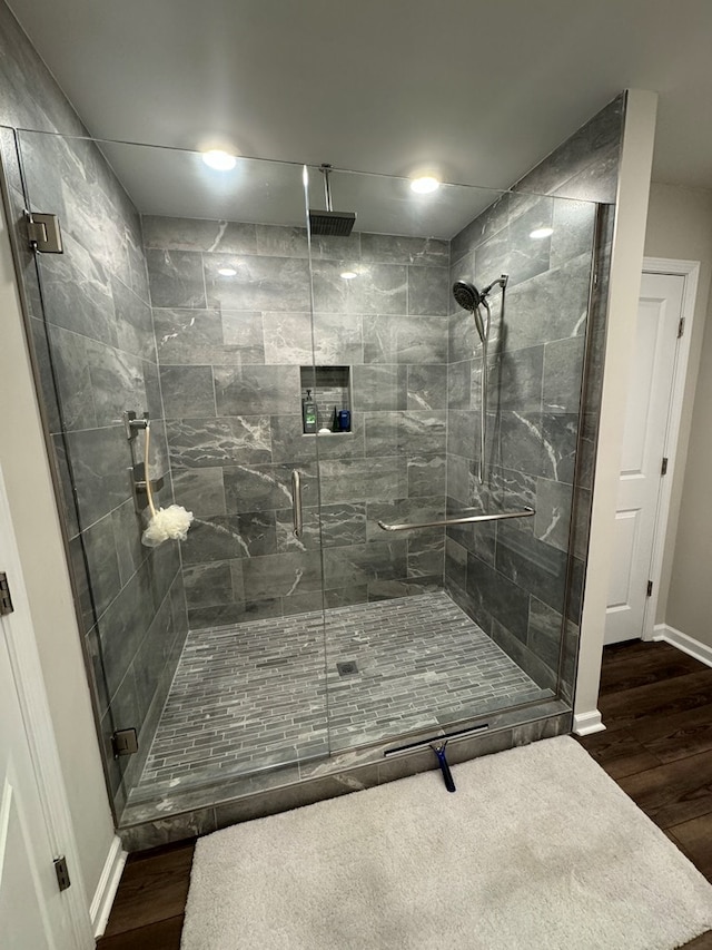 bathroom with a shower stall, baseboards, and wood finished floors