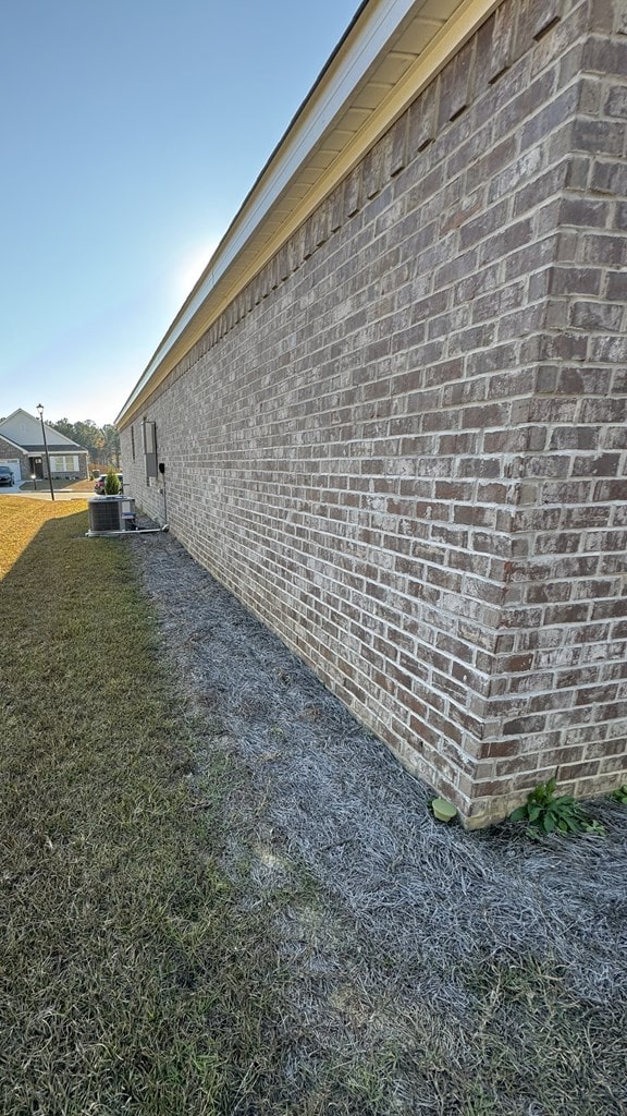 view of home's exterior featuring cooling unit, a lawn, and brick siding