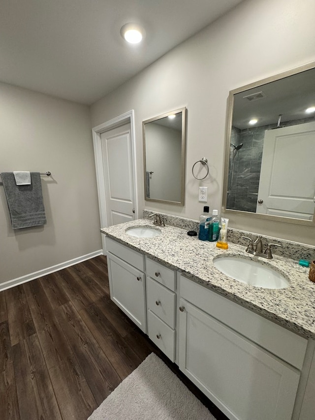 full bath with visible vents, tiled shower, wood finished floors, and a sink