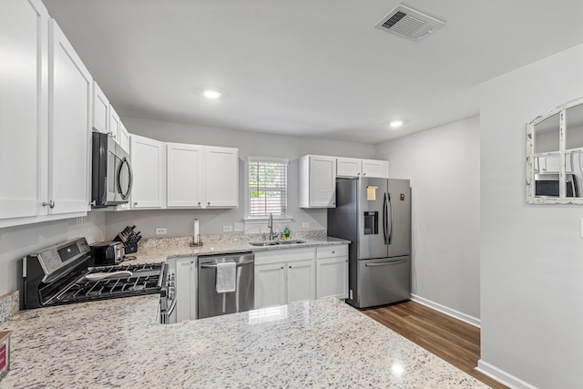 kitchen with light stone countertops, sink, white cabinetry, and appliances with stainless steel finishes