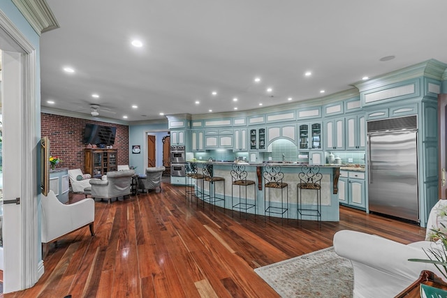 109 Royal Highlands Ln, Dothan, AL 36305 - kitchen featuring stainless steel appliances, ceiling fan, dark wood finished floors, a kitchen bar, and a fireplace
