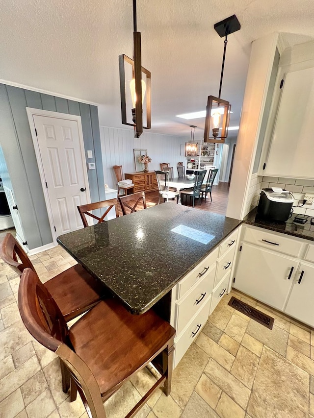 601 6th Ave, Ashford, AL 36312 - kitchen with stone tile floors, a peninsula, a breakfast bar, white cabinets, and a textured ceiling