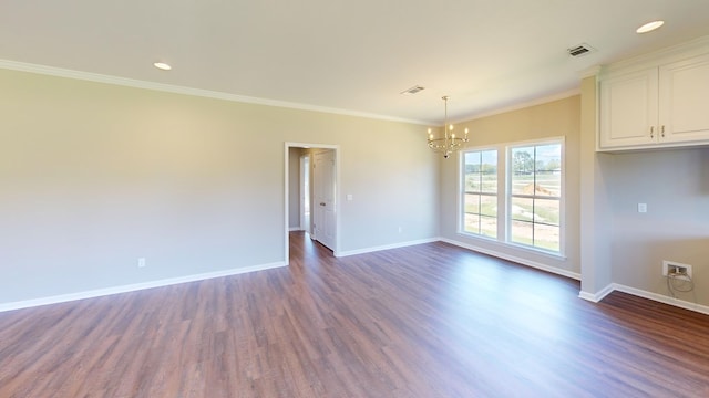 spare room featuring dark hardwood / wood-style floors, crown molding, and an inviting chandelier