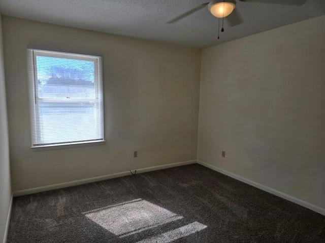 spare room featuring a textured ceiling, dark colored carpet, and ceiling fan