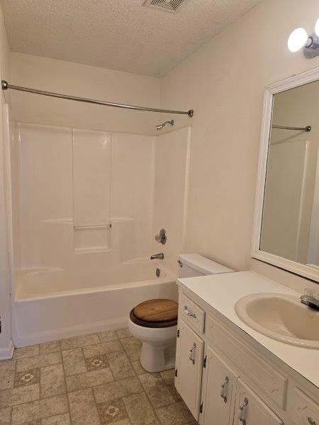 full bathroom featuring a textured ceiling, toilet, vanity, and  shower combination