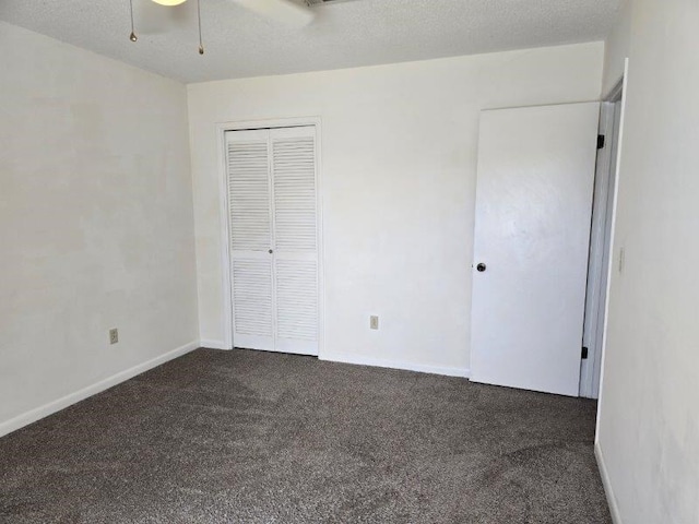 unfurnished bedroom with a textured ceiling, ceiling fan, a closet, and dark colored carpet