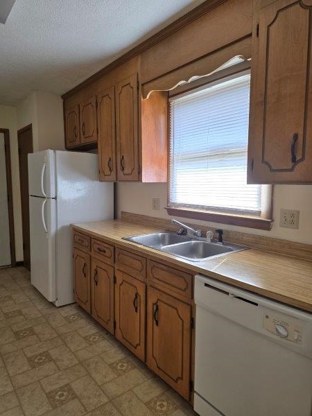 kitchen featuring a textured ceiling, sink, and white appliances