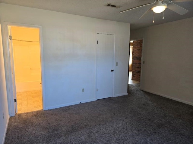 unfurnished bedroom with ceiling fan, connected bathroom, and dark carpet