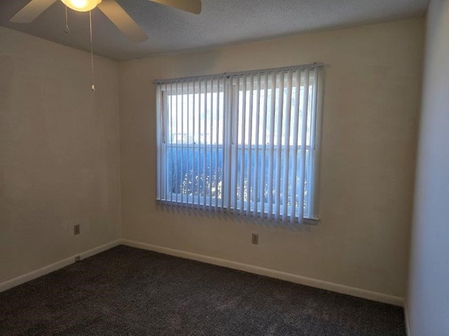 spare room with ceiling fan and dark carpet