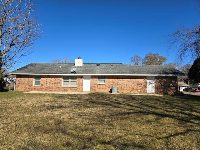 rear view of property with central AC unit and a yard