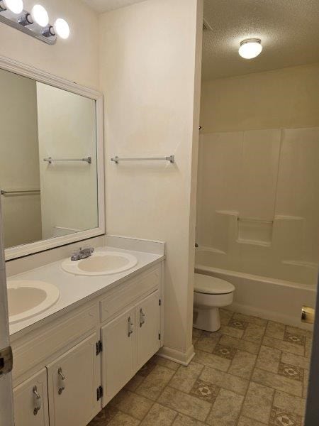 full bathroom with tub / shower combination, a textured ceiling, toilet, and vanity