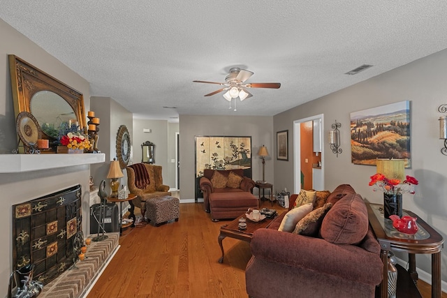 303 Denise St, Dothan, AL 36305 - living room with a ceiling fan, a fireplace with raised hearth, wood finished floors, and a textured ceiling