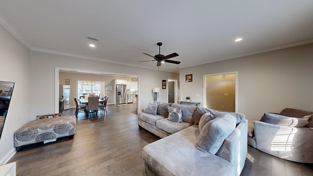 living room with ceiling fan, ornamental molding, and dark wood-type flooring