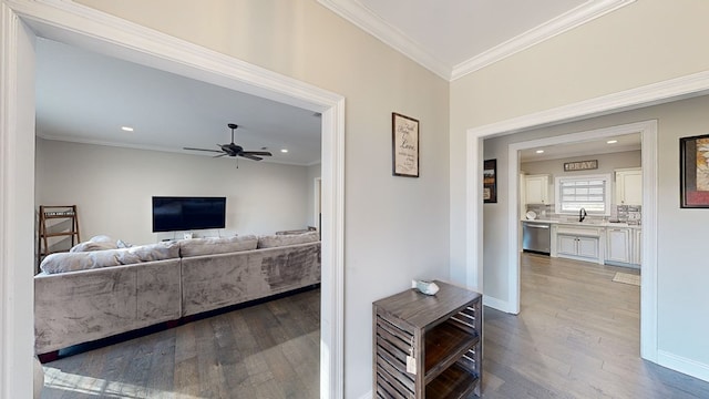 living room with hardwood / wood-style floors, ceiling fan, crown molding, and sink