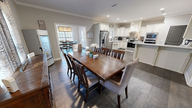 dining space with sink, dark wood-type flooring, and ornamental molding