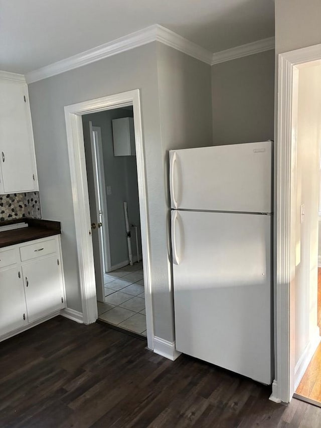 kitchen featuring decorative backsplash, dark hardwood / wood-style flooring, ornamental molding, white cabinets, and white fridge