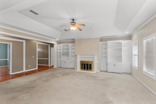 unfurnished living room featuring a raised ceiling, crown molding, light hardwood / wood-style flooring, ceiling fan, and a textured ceiling