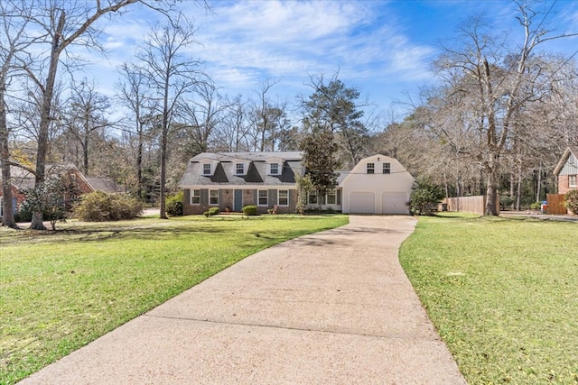 view of front of home with a front yard, brick siding, fence, and driveway