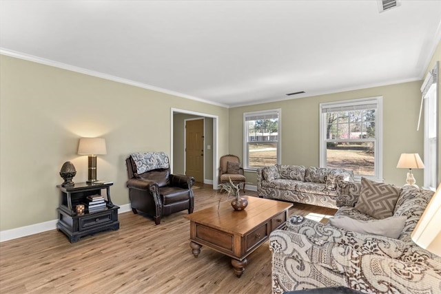 living area featuring visible vents, ornamental molding, light wood-style flooring, and baseboards