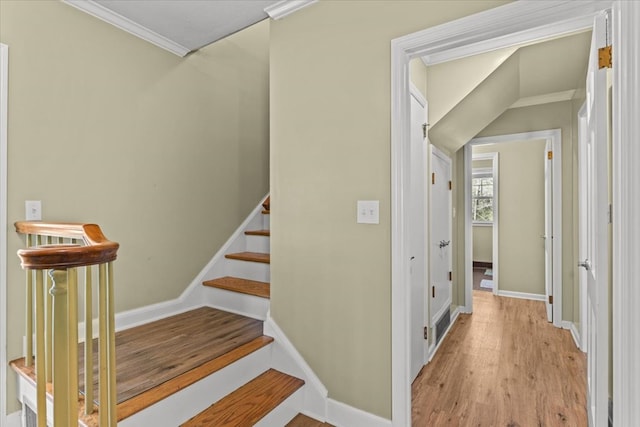 staircase with ornamental molding, baseboards, and wood finished floors