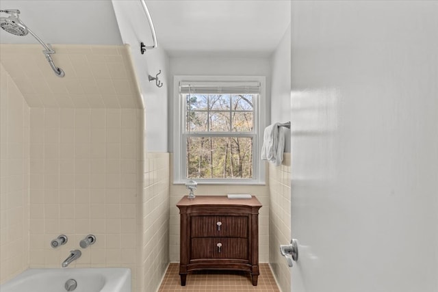 bathroom with a wainscoted wall, shower / tub combination, tile walls, and tile patterned floors