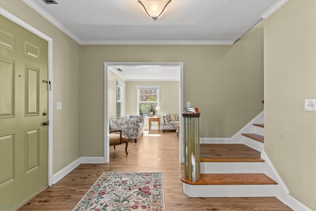 entryway with ornamental molding, stairway, baseboards, and wood finished floors