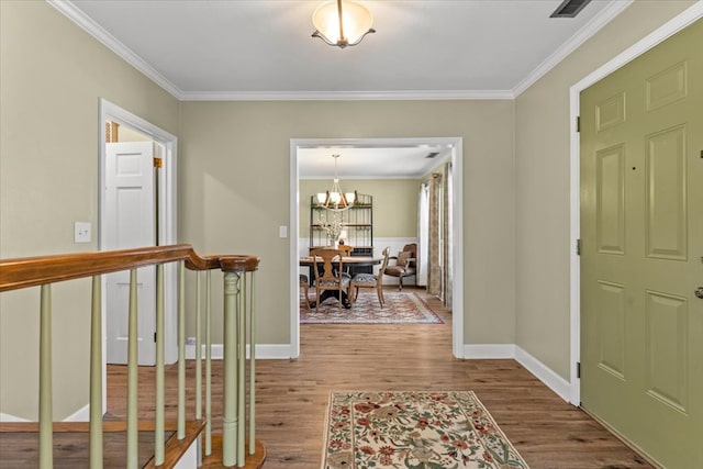 entryway featuring baseboards, ornamental molding, wood finished floors, and a notable chandelier