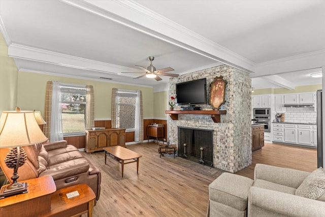 living area featuring ornamental molding, light wood-type flooring, and wainscoting