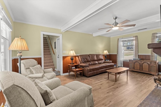 living area with a wainscoted wall, wood finished floors, visible vents, stairway, and beamed ceiling