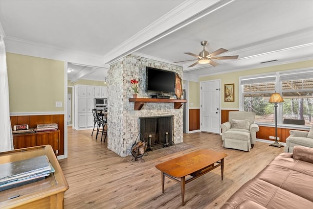 living area featuring a wainscoted wall, a large fireplace, wood finished floors, and visible vents