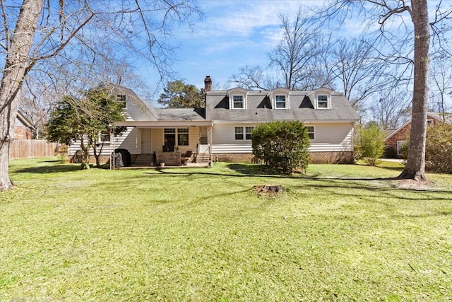 back of property with entry steps, a chimney, fence, and a lawn