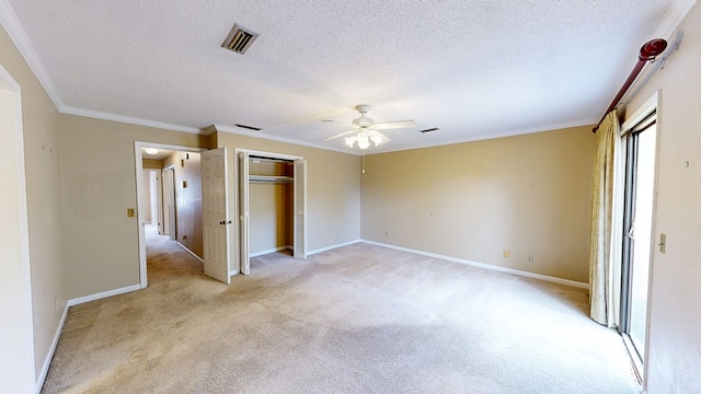 unfurnished bedroom featuring crown molding, a textured ceiling, and light carpet