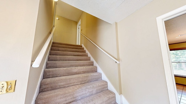 staircase with baseboards and a textured ceiling