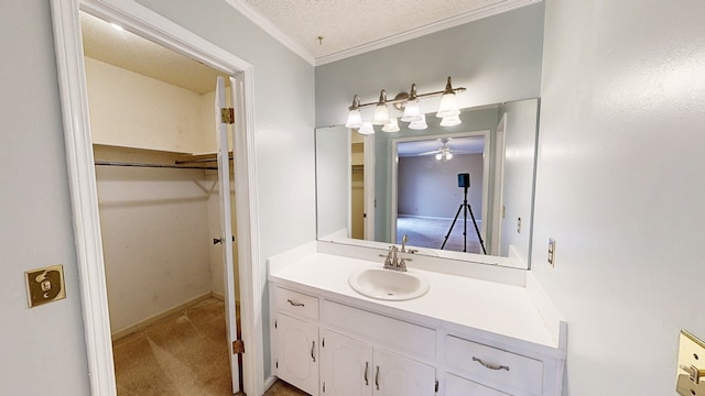 bathroom with crown molding, vanity, a textured ceiling, a ceiling fan, and a spacious closet