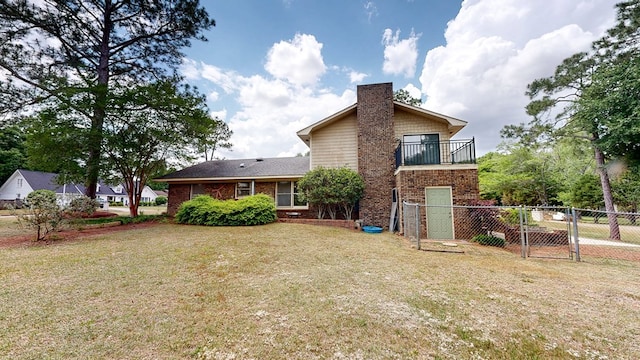 back of house with a yard, fence, a gate, and a balcony