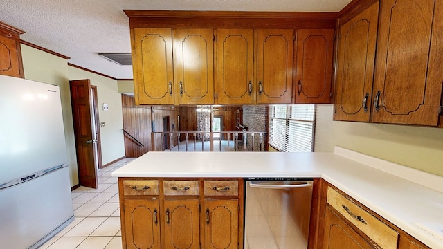 kitchen featuring brown cabinetry, freestanding refrigerator, a peninsula, light tile patterned floors, and dishwasher