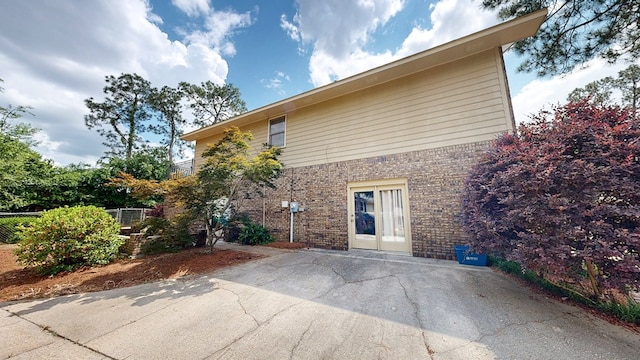 exterior space with brick siding, fence, and a patio area