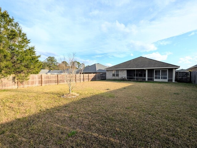 view of yard featuring a sunroom and a fenced backyard