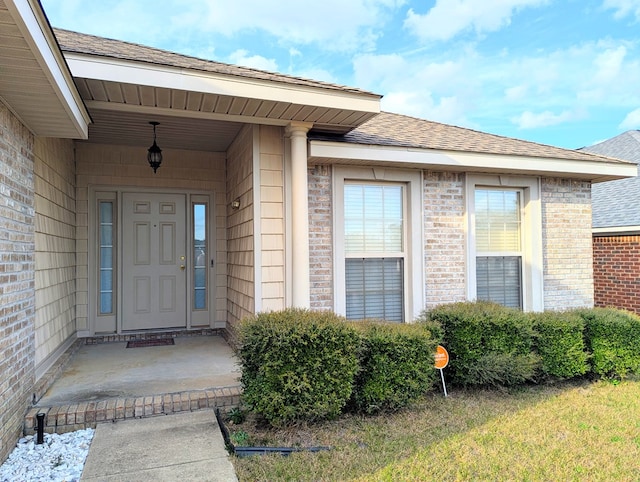 entrance to property featuring brick siding and roof with shingles