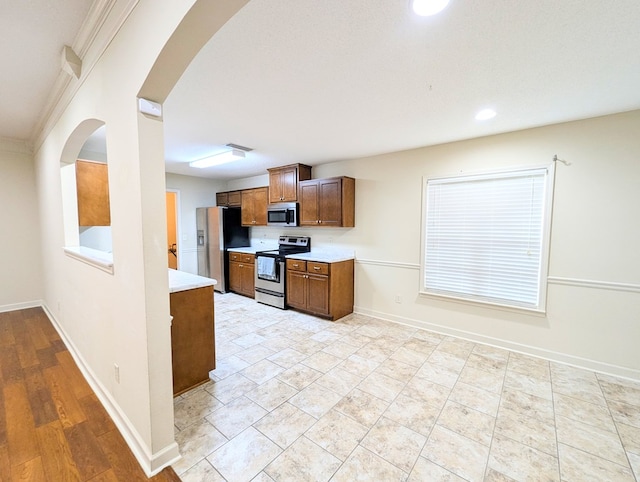 kitchen with arched walkways, stainless steel appliances, light countertops, visible vents, and baseboards